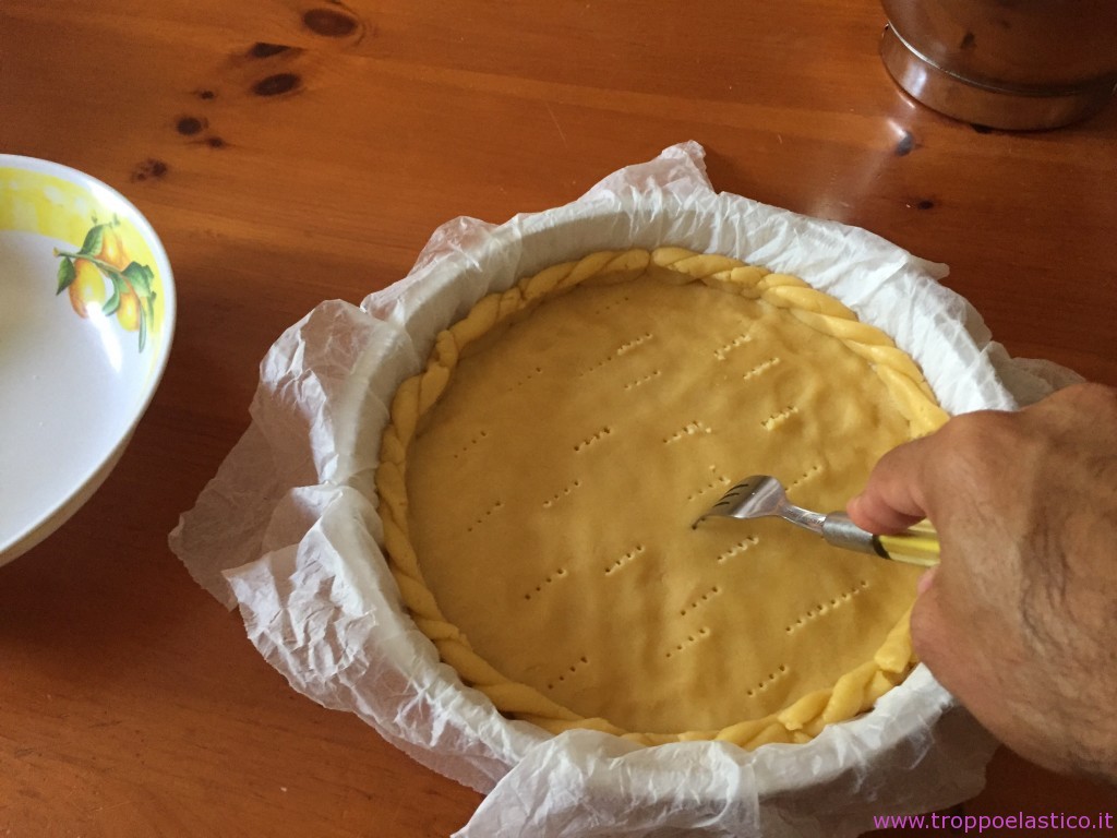 Dopo che la pasta avrà riposato in fresco sarà più facile da lavorare. Foderare una teglia per crostate con carta forno o in alternativa imburrare e infarinare. Stendere la pasta frolla formando un leggero bordo sollevato. Bucare tutta la base con una forchetta così da evitare se si gonfi in cottura